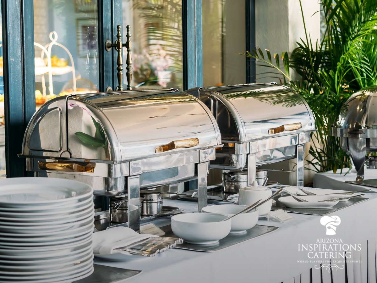 Elegant buffet setup for DIY wedding catering with stainless steel chafing dishes and neatly arranged tableware